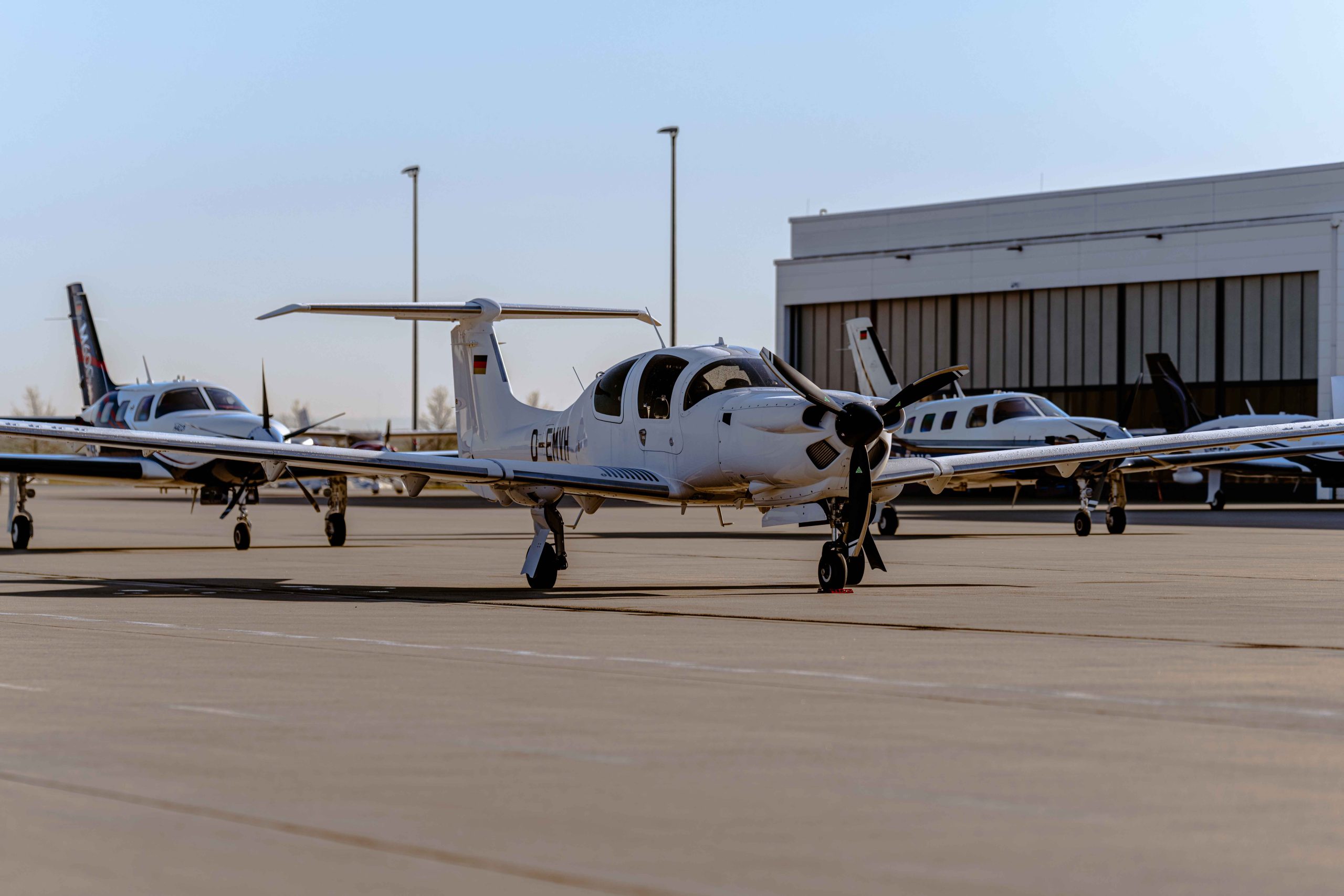 Diamond DA 50 RG auf dem Vorfeld eines Flughafens. Im Hintergrund mehrere Piper PA-46 Modelle.