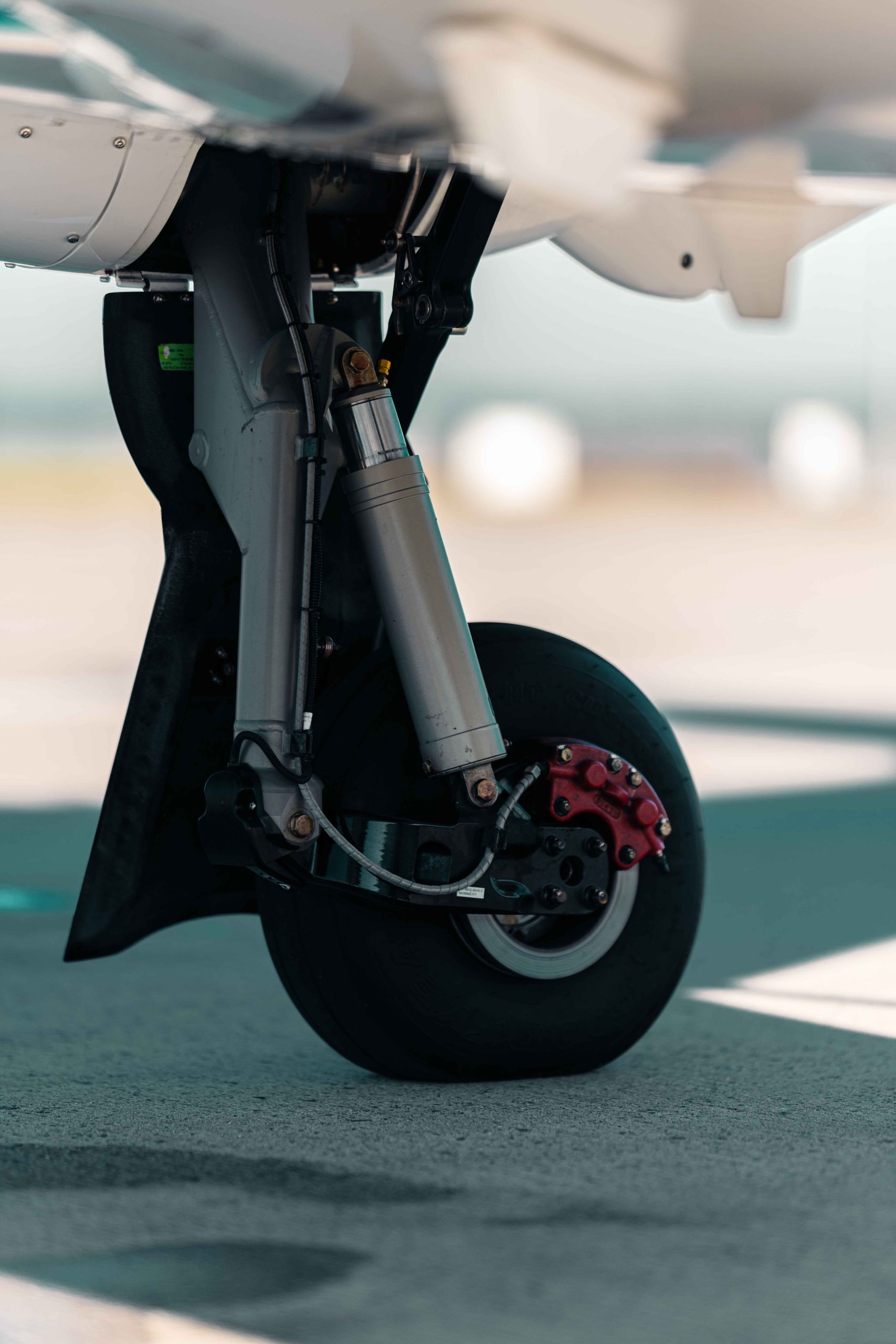 Detailaufnahme des vorderen Einziehfahrwerks der Diamond DA50 RG mit Federung, Bremssystem und Flugzeugrad auf dem Vorfeld eines Flughafens